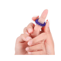 Bague hérissée bleue glissée sur le doigt, illustrant son action de massage stimulant.