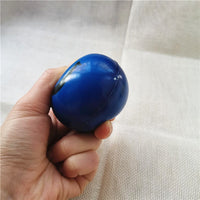 Balle anti-stress Smiley bleue pressée dans la main, montrant sa souplesse