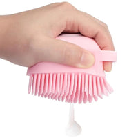 Brosse de douche doseuse rose, pressée pour faire sortir le savon à travers les picots