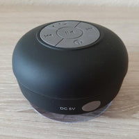 Enceinte portable waterproof noire avec ventouse, entrée DC 5V visible sur le côté