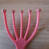 Gros plan sur la griffe masseuse de tête rose munie de cinq billes métalliques pour la détente du cuir chevelu