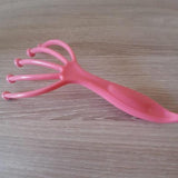 Griffe masseuse de tête rose vue de côté, avec poignée ergonomique et branches flexibles pour un massage relaxant