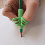 Guide doigt vert en utilisation pour écrire, favorisant une meilleure position des doigts sur le crayon