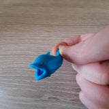 Guide doigt poisson bleu tenu du bout des doigts, idéal pour corriger la prise en main d’un stylo ou crayon
