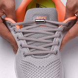 Gros plan sur une chaussure de sport grise munie de lacets élastiques avec embout métallique, offrant un laçage rapide et sécurisé