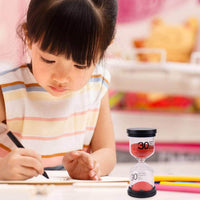 Une fillette concentrée sur son exercice, accompagnée d’un sablier de 30 minutes pour mieux organiser son temps d’apprentissage.