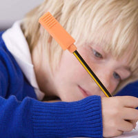 Un enfant utilise un embout à mâchouiller brique orange sur son crayon