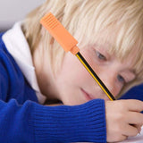 Un enfant utilise un embout à mâchouiller brique orange sur son crayon